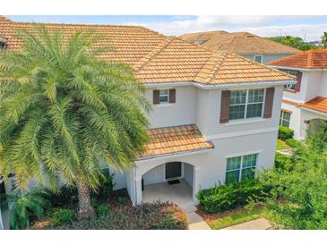 Charming two-story townhome featuring a tile roof, arched entry, and tropical landscaping at 4865 Clock Tower Dr, Kissimmee, FL 34746