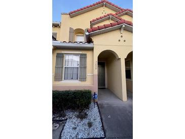 Charming townhouse with a red tile roof, arched entry and green shutters, creating an inviting curb appeal at 5290 Paradise Cay Circle, Kissimmee, FL 34746