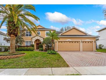 Charming tan two-story home with a three-car garage, lush lawn, and mature landscaping at 8606 Terrace Pines Ct, Orlando, FL 32836