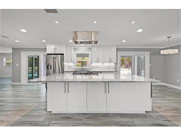 Bright, open kitchen with white cabinets, stainless appliances, and large center island at 8908 Turnberry Ct, Orlando, FL 32819