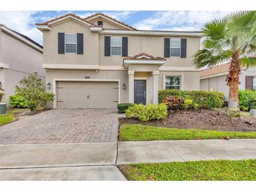 Charming two-story home with neutral stucco, dark shutters, brick driveway and well maintained landscaping at 1616 Oak Blossom Dr, Davenport, FL 33837