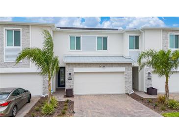 Townhome exterior featuring a two-car garage, neutral paint, and stone accents at 171 Bogey Dr, Davenport, FL 33896