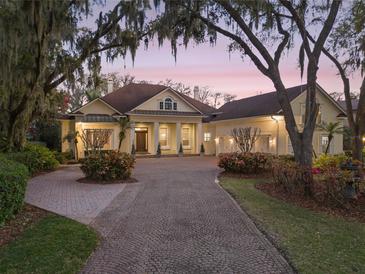 Stunning home featuring a circular driveway and a meticulously landscaped front yard with mature trees and lush greenery at 10411 Hart Branch Cir, Orlando, FL 32832