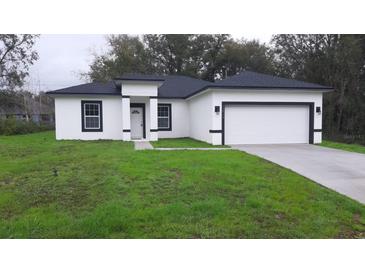 Attractive new home with a crisp white exterior, black trim, and a well-manicured lawn at 12793 Sw 43Rd Cir, Ocala, FL 34473