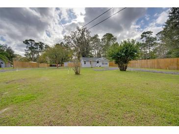 Charming single-story home featuring a well-maintained lawn and mature trees, enhanced by a wooden fence at 224 E Kelly Park Rd, Apopka, FL 32712