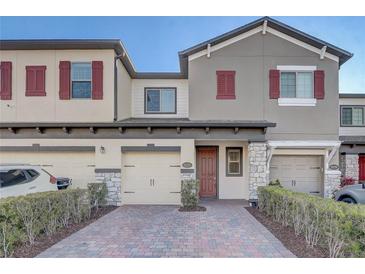 Charming townhome showcasing a brick driveway, stone accents, and a stylish red front door and shutters at 2725 Econ Landing Blvd, Orlando, FL 32825