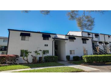 Two-story condo features classic black awnings, clean white paint, and lush landscaping at 4205 S Semoran Blvd # 3, Orlando, FL 32822