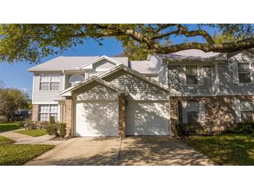 Charming townhome showcasing dual garages, brick accents, and mature trees providing ample shade at 5258 Tunbridge Wells Ln # 1902, Orlando, FL 32812