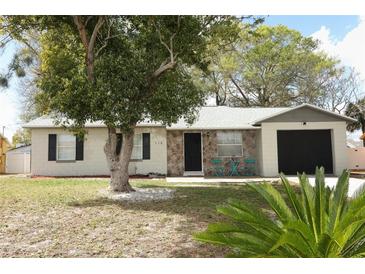 Charming single-story home with stone facade and a well-maintained front yard with mature shade trees at 558 Tyler Ave, Deltona, FL 32725