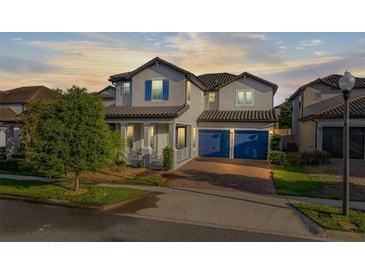 Two-story home featuring a tile roof, brick driveway, blue shutters and a two-car garage at 14602 Winter Stay Dr, Winter Garden, FL 34787