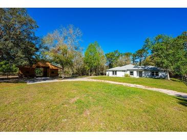 Charming single story home with a rustic barn and a well-maintained green lawn under a clear blue sky at 20773 Starry St, Orlando, FL 32833