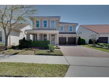Charming two-story home with a well-manicured lawn, flowerbeds, and a two-car garage on a brick paved driveway at 2724 Sarzana Ln, Apopka, FL 32712