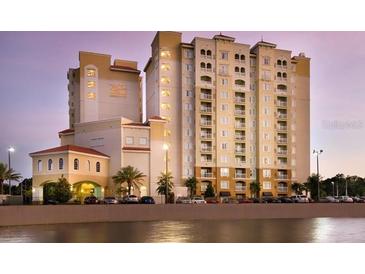 Beautiful exterior view of a resort hotel with a variety of palm trees and a row of parked cars at 7395 Universal Blvd # 104, Orlando, FL 32819