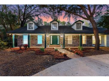 Charming brick home featuring lush landscaping, dormer windows, and a welcoming front porch with brick walkway at 140 Sweet Bay Cir, Lake Mary, FL 32746