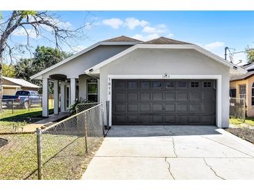 Charming single-story home with a gray exterior, dark garage door, and a well-maintained front yard at 1613 N Lakewood Ave, Ocoee, FL 34761