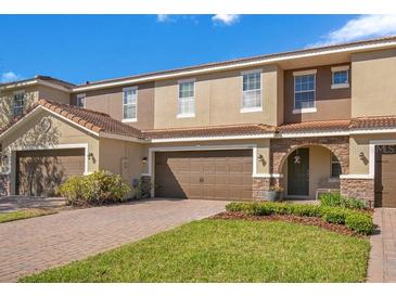 Townhouse exterior with brown garage doors, stone accents, and a well-maintained lawn at 2165 Leather Fern Dr, Ocoee, FL 34761