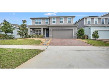 Charming two-story home boasts a well-manicured lawn and a brick-paved driveway at 3005 Slough Creek Dr, Kissimmee, FL 34744