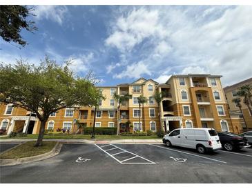 Exterior of a light yellow building with balconies, palm trees, and a parking lot in front at 4814 Cayview Ave # 407, Orlando, FL 32819