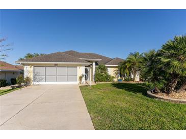 Charming single-story home with a well-manicured lawn, screened garage, and lush landscaping at 5025 St Andrews Arc, Leesburg, FL 34748