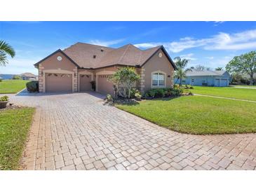 Charming home featuring a three-car garage, brick driveway and lush landscaping at 10544 Spring Lake Dr, Clermont, FL 34711