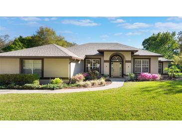 Inviting single-story home featuring a well-manicured lawn and colorful landscaping at 17220 Countrybrook Ln, Orlando, FL 32820