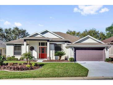 Charming single-story home boasts a well-manicured lawn and a bright red front door at 24515 Bocage Way, Leesburg, FL 34748