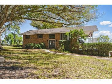 Charming brick two-story home with a lush front yard and mature trees, offering a serene and inviting curb appeal at 13224 Casper Ln, Clermont, FL 34711