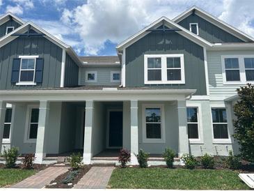 Charming two-story townhome featuring a covered porch, lush landscaping, and a welcoming entrance at 13809 Luna Harvest Ave, Winter Garden, FL 34787