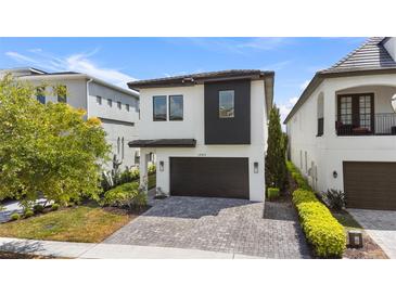 Modern two-story home with a dark garage door, white and dark grey exterior, and a well-maintained front yard at 1543 Corolla Ct, Reunion, FL 34747