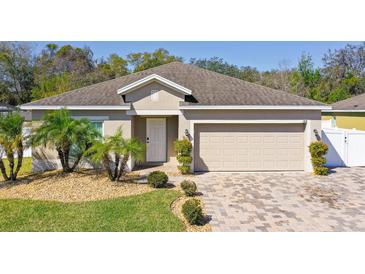 Charming single-story home featuring a well-maintained lawn, paver driveway, and an attached two-car garage at 188 Whispering Pines Way, Davenport, FL 33837