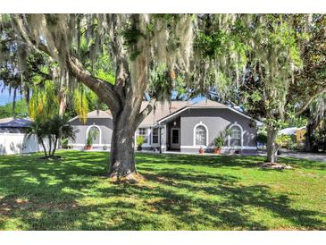 Charming gray home with arched windows and mature landscaping at 24 Cypress Ave, St Cloud, FL 34769