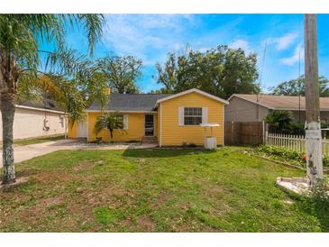 Charming yellow single-story home featuring a well-maintained lawn, palm tree, and inviting curb appeal under a sunny sky at 5424 Blue Grass St, Orlando, FL 32810