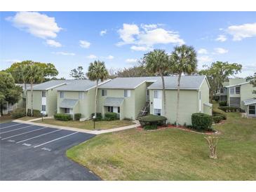 Exterior view of condos with ample parking, well maintained lawn and shrubbery, and some palm trees at 543 Fairways Dr # B, Ocala, FL 34472