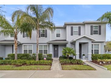 Inviting townhome featuring a manicured lawn, gray siding, and dark shutters at 6067 Blue Lily Way, Winter Garden, FL 34787