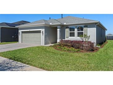 Charming home featuring a well-manicured lawn, two-car garage, and neutral-colored facade at 637 Conservation Blvd, Groveland, FL 34736