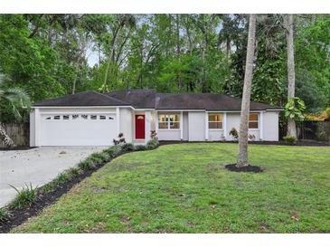 Charming single-story home with a well-manicured lawn, red door, and attached garage at 703 Sailfish Rd, Winter Springs, FL 32708