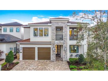 Stunning two-story home with stone accents, balcony, two-car garage, and a beautifully landscaped front yard at 1003 Jack Nicklaus Ct, Kissimmee, FL 34747