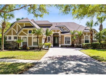 Beautiful, sprawling home featuring tropical landscaping, stone accents, and a brick-paved driveway at 1720 Bridgets Ct, Kissimmee, FL 34744