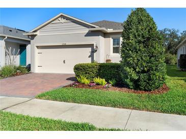 Charming home with brick-paved driveway, complemented by manicured landscaping and lush green grass at 17398 Blazing Star Cir, Clermont, FL 34714