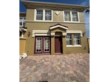 Two-story townhome with a brick driveway and classic architectural details at 3026 Bella Vista Dr, Davenport, FL 33897