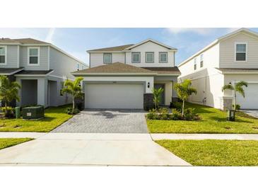 Charming two-story home featuring a well-manicured lawn and a paved driveway leading to an attached two-car garage at 3428 Lilac Way, Davenport, FL 33897