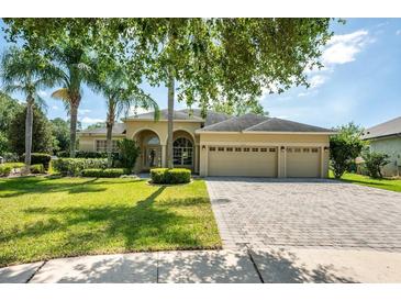 Inviting home featuring a three-car garage, manicured lawn and mature landscaping with palm trees at 5055 Coveview Dr, St Cloud, FL 34771