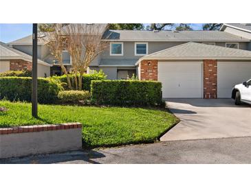 Well-maintained home exterior with green lawn, mature landscaping, and brick accented garage at 610 Chestnut Oak Cir # 114, Altamonte Springs, FL 32701