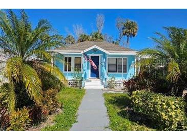 Charming turquoise home with an American flag, lush landscaping, and a welcoming pathway at 723 Dougherty St, New Smyrna Beach, FL 32168