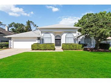 Charming single-story home boasts a lush lawn and manicured hedges framing arched windows at 824 Palm Cove Dr, Orlando, FL 32835
