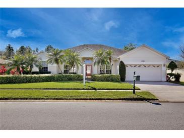 Charming single-story home featuring a well-manicured lawn, mature palm trees, and a brick driveway at 9102 Shadowbrook Trl, Orlando, FL 32825