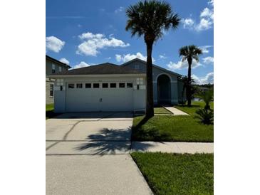 Charming single-story home featuring a two-car garage, well-manicured lawn, and palm trees at 1623 Bridgeview Cir, Orlando, FL 32824