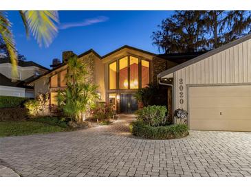 Stunning home exterior featuring stone accents, large windows, lush landscaping, and a paver driveway at 2020 Venetian Way, Winter Park, FL 32789
