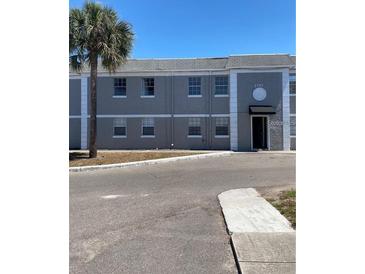 Low-rise residential building in gray paint with large tree in view at 2751 L B Mcleod Rd # 2751, Orlando, FL 32805