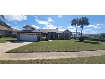 Charming single-story home with a well-manicured lawn, palm trees, and attached two car garage at 4421 Steed Ter, Winter Park, FL 32792